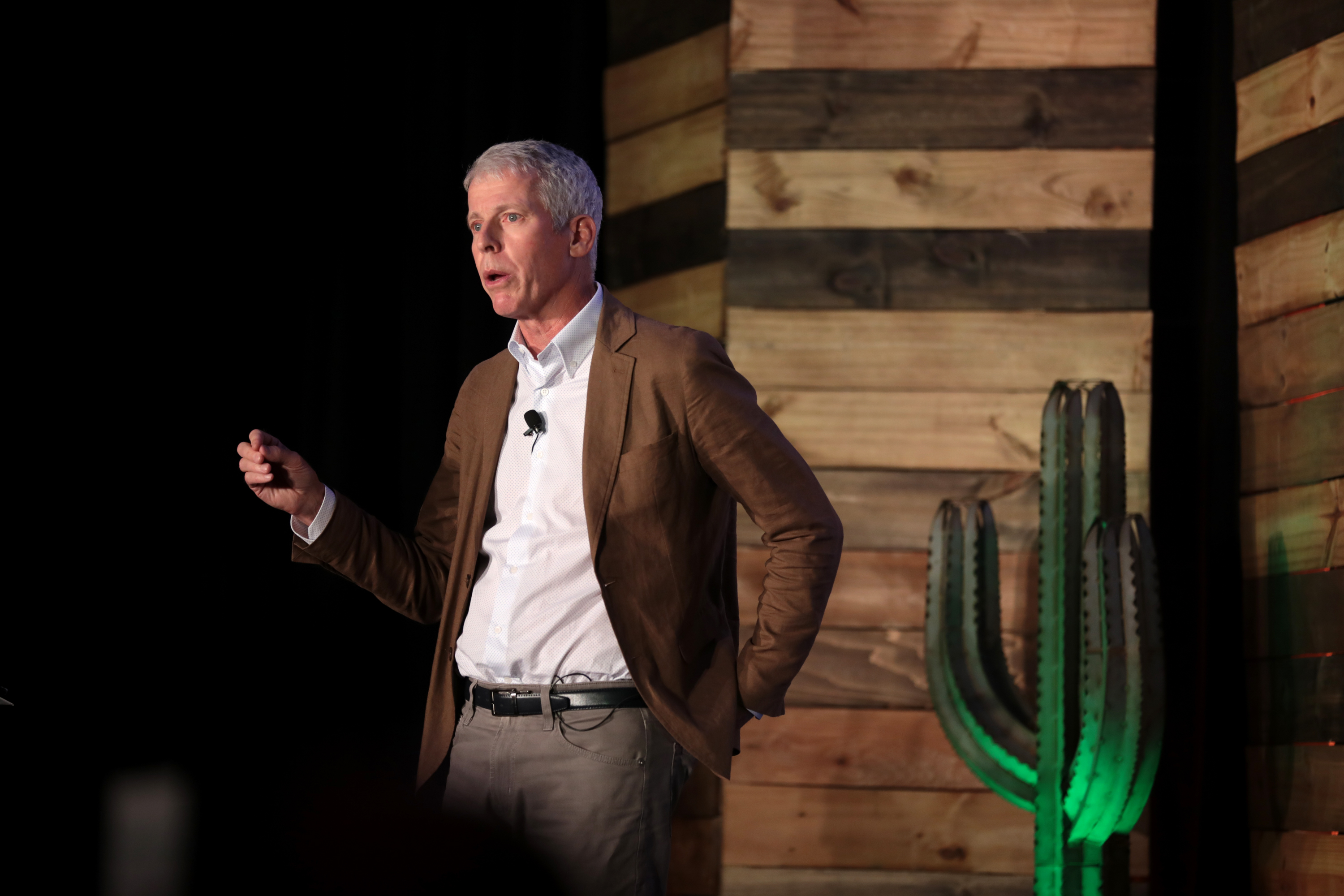 Chris Wright speaks onstage with a cactus behind him. Chris Wright speaks onstage with a cactus behind him.