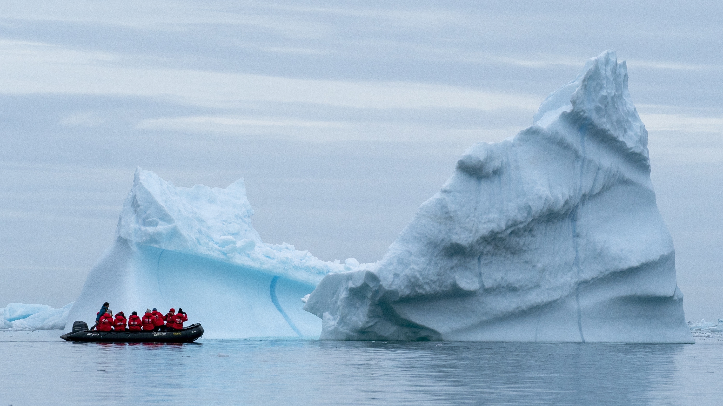 A group of travelers examine an iceberg in the Scoresby Sund of Greenland. A group of travelers examine an iceberg in the Scoresby Sund of Greenland.