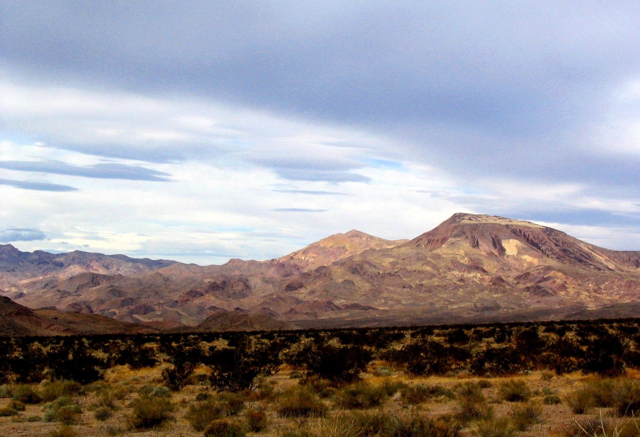 A view of the Ivanpah Mountains in California's Mojave National Preserve with blue sky and clouds. A view of the Ivanpah Mountains in California's Mojave National Preserve with blue sky and clouds.