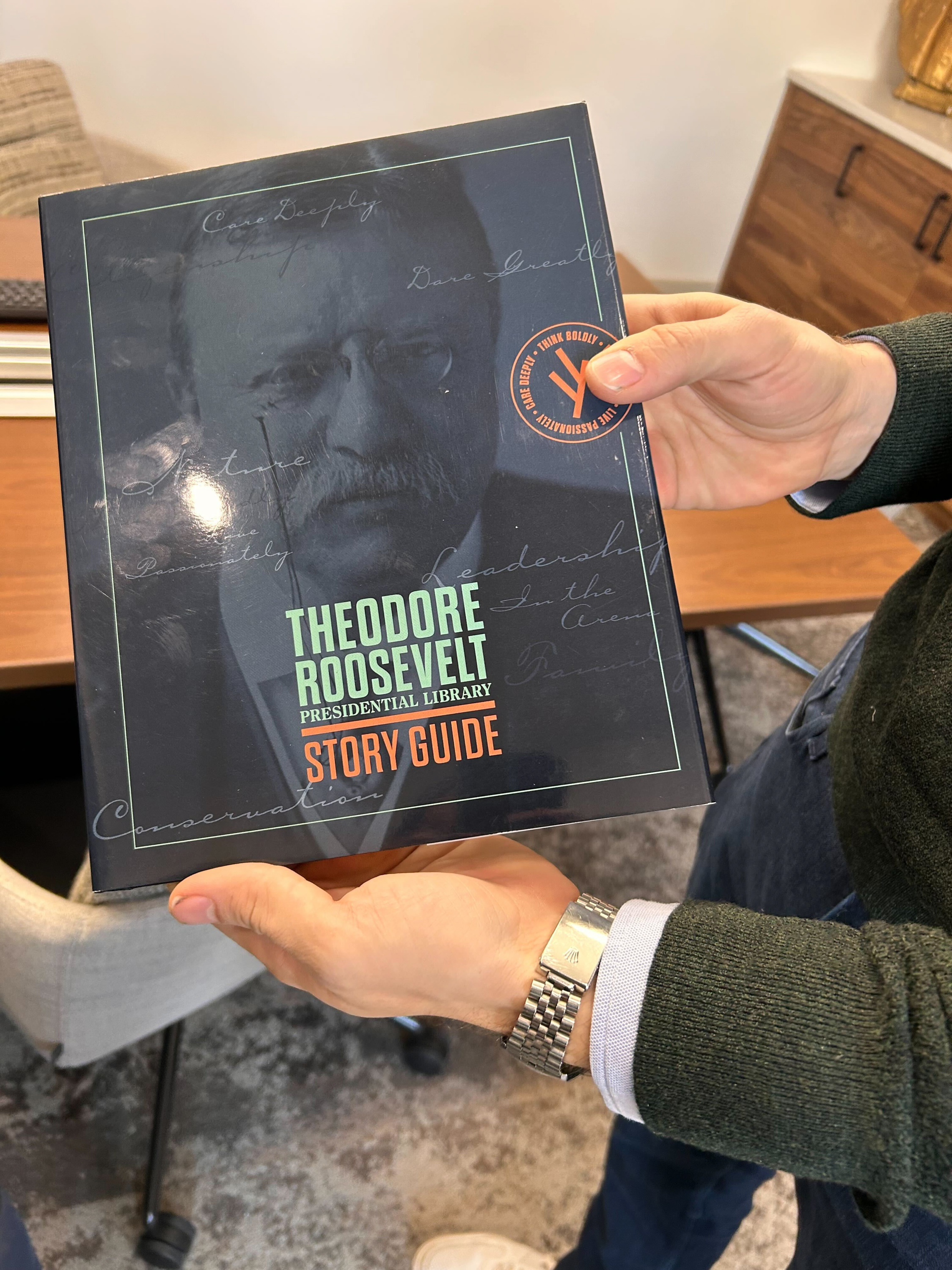 A person holds a story guide for the Theodore Roosevelt Presidential Library. A person holds a story guide for the Theodore Roosevelt Presidential Library.