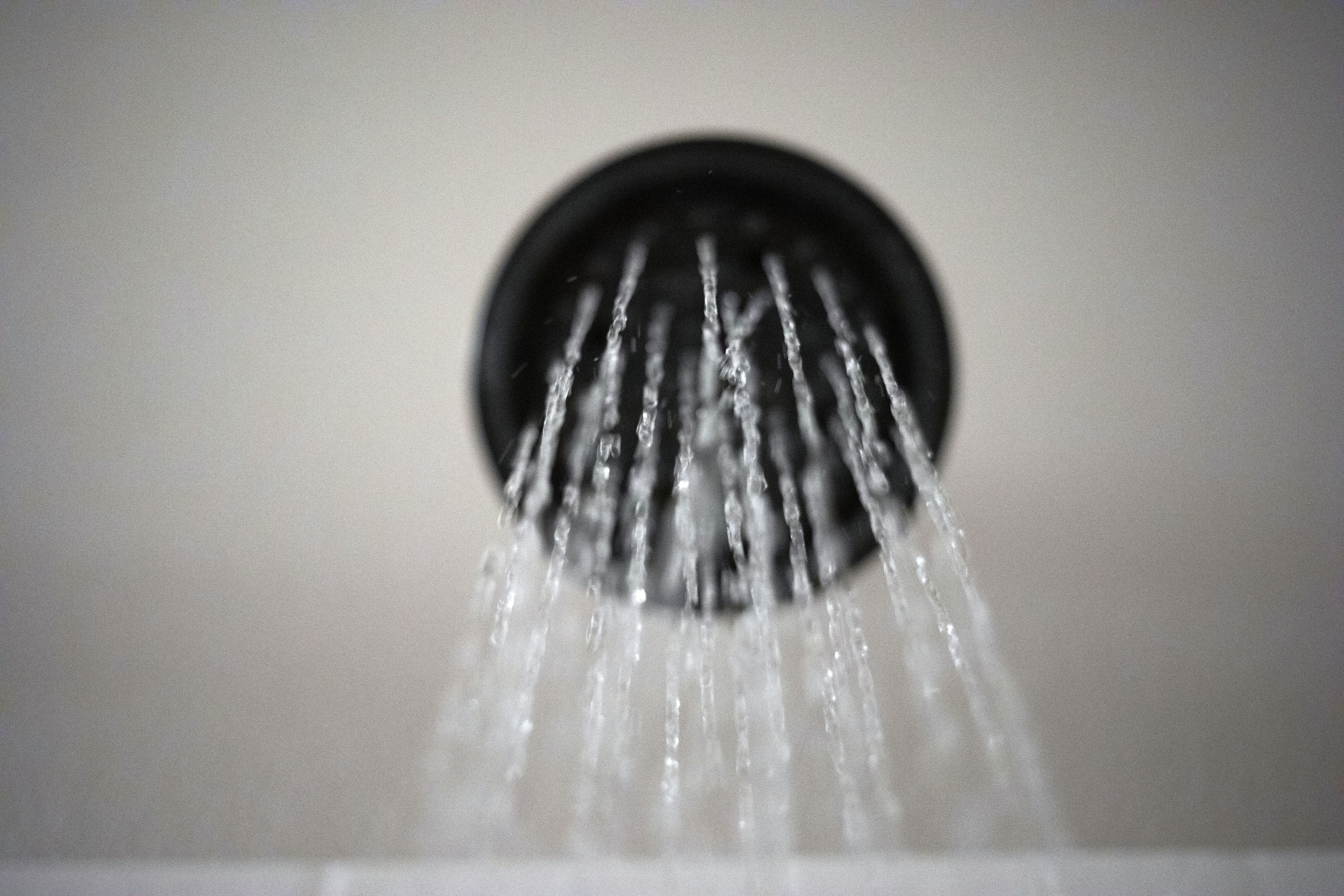 Water flows from a showerhead. Water flows from a showerhead.
